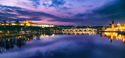 Fototapeta na wymiar Prague evening panorama. Prague Castle with Carles Bridge reflect in Vltava river during sunset