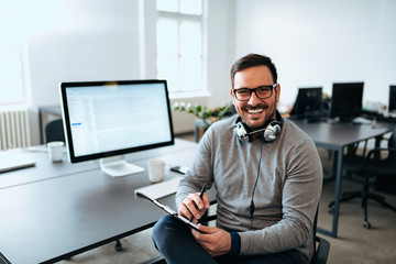 Young casual entrepreneur at modern office, looking at camera.