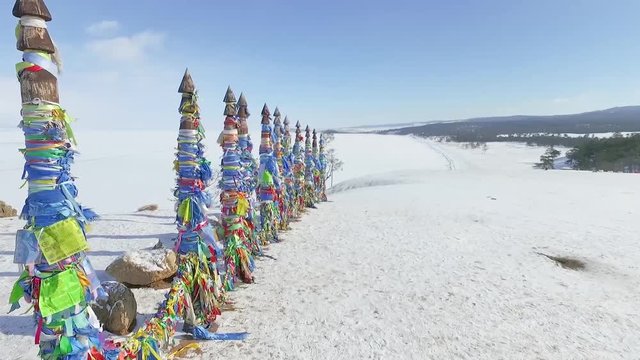 Wooden poles on the island of Olkhon, interlaced with numerous ribbons of different colors of blue, orange, red, green, and all of them are developed in the wind.
