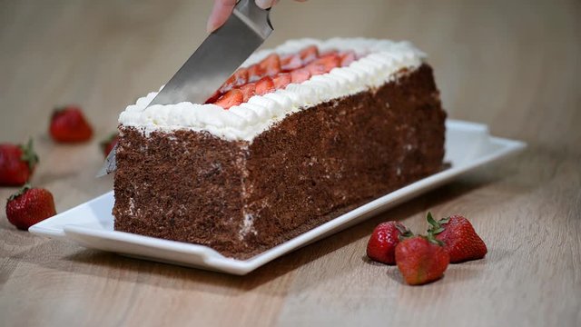 Cutting chocolate cake with strawberries.