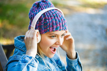 Girl listens to music in headphones. Listening to music.Autumn melody concept. Young woman with big headphones. Cheerful girl rejoicing listening music in headphones smiling. Fall and autumn season.