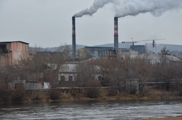 Fototapeta na wymiar Two smoking funnels with river foreground
