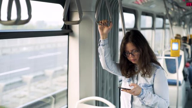 Young girl addictive to a cell phone typing in the tram.