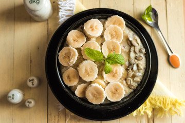 Porridge with fresh banana slices and seeds in the black bowl