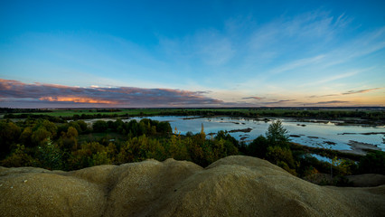 Sandy hills. Lake in the Sandy canyon. Warm colors background. Yellow sandstone textured mountain, white thin sand dune, bright sky. Sunshine landscape