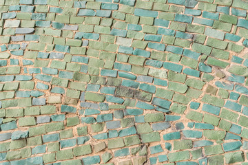 green Surface of old crumbling abstract decorative mosaic as background. Multicolored ceramic stones on wall building