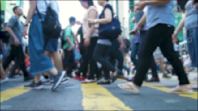 Anonymous crowd of pedestrians cross a busy city intersection on a summer evening. Pedestrians walkers. Slow motion shot. Urban lifestyle background.