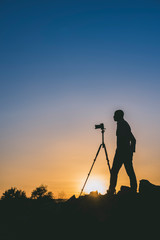 Silhouette of black photographer at sunset