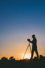 Silhouette of black photographer at sunset