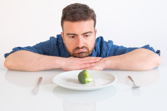 Sad And Hungry Man Watching Poor Diet Meal