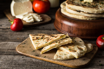 Pita bread on wooden board with feta cheese and tomatoes and pepper. Still life of food. Georgian cuisine. Spanish food. National cuisine. Traditional dish on wooden table. Mediterranean cuisine.
