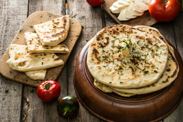 Pita bread on wooden board with feta cheese and tomatoes and pepper. Still life of food. Georgian cuisine. Spanish food. National cuisine. Traditional dish on wooden table. Mediterranean cuisine.