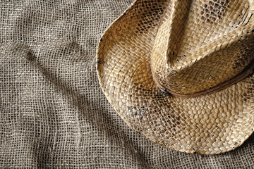 Fototapeta premium Western style straw hat on burlap. Top down view.