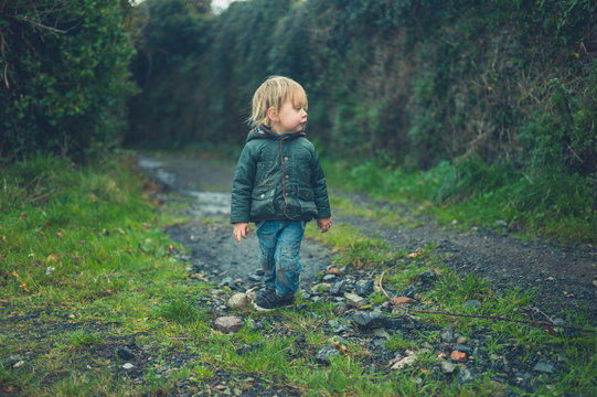 Toddler standin in the countryside on gravel road