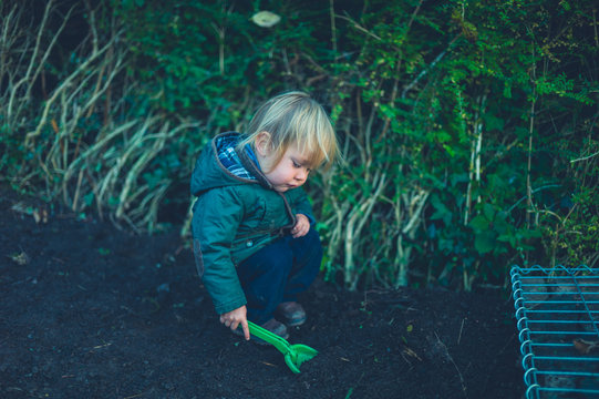 Toddler standing in garden with toy spade