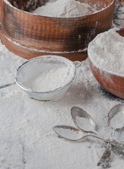 Still life with flour and spoons with a roll, a strainer. supplied on a wooden basis
