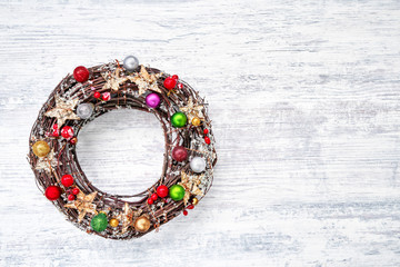 Christmas wreath with decoration on white wooden background. Copy space, top view.