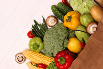 Fresh vegetables in a paper bag on a wooden table. Top view.