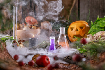 Magic glowing pumpkin for Halloween on the witch's table with ingredients for potions.