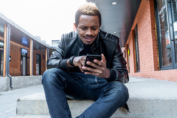 Close up of dark-skinned man looking at mobile phone screen.
