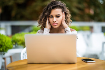 Young latin curly working woman and laptop computer he headache unhappy on job in cafe