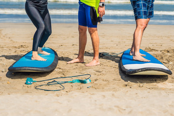 Young woman and man training to stand on the surf before the first surfing lesson