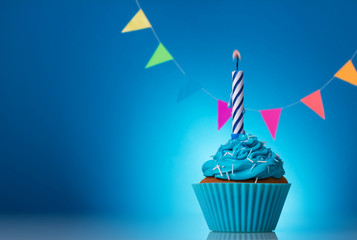 Festive cupcakes for a birthday on a blue background with colorful garland and candle