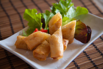 Spring rolls cut into halves on a plate with garnish salad leaves