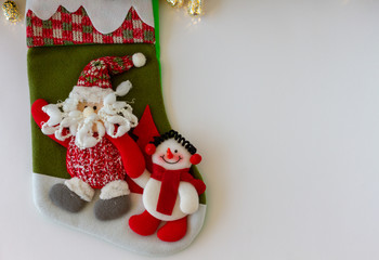 Green Christmas Stocking with Santa and Snowman. Golden Tinsel. White Background. Copy Space. Top View
