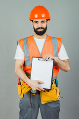 A builder in an orange helmet on a gray background signs something