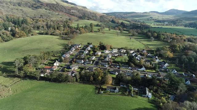 Aerial footage over the rural village of Fintry with views to the Campsie Fells. Flying right.