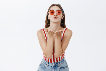 Indoor shot of tender and feminine stylish european woman in sunglasses and striped top bending...