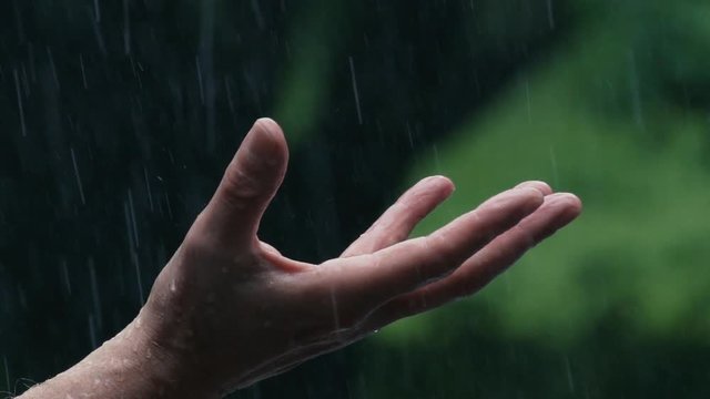 Slow motion 180fps: Man holds his open  hand / palm out in the  pouring rain