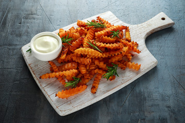 Baked butternut squash fries with sea salt and rosemary. Pumpkin chips on white wooden board.