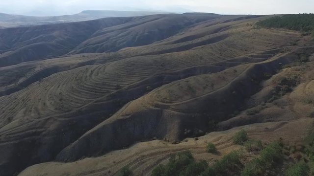 Wavy hills panorama, aerial view at sunset time. Shot. Wavy forest mountain landscape, aerial view. Tender sky colours, bright sunlight. Peaks of Caucasus mountains,