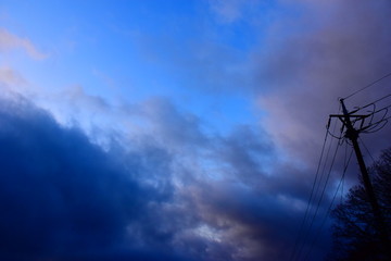 Fototapeta na wymiar 早朝の青空と暗い雲と、右側に電柱のシルエット