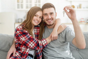 Young happy couple hugging, showing keys to new house