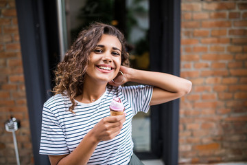 Mixed race curlu Woman eating Ice cream on vacation travel. Smiling girl having fun eating icecream outdoors during holidays .