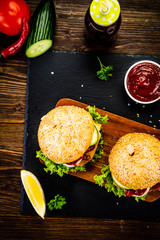 Tasty burgers with chips served on cutting board on stone plate