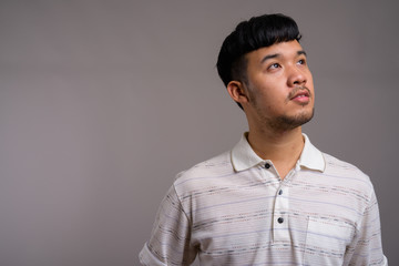 Portrait of young Asian man against gray background