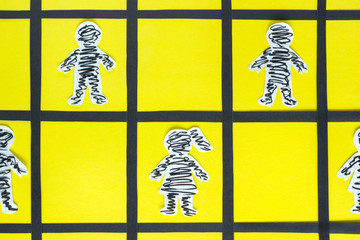 Paper prisoners behind the bar on the yellow background.
