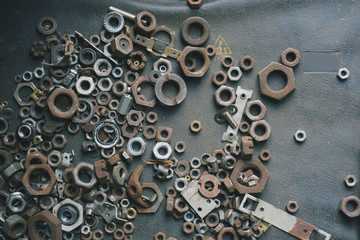Many rusty screw-nuts on a dark surface. Grunge background.
