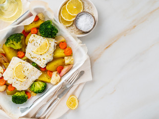 Fish cod baked in the oven with vegetables - healthy diet healthy food. Light white marble table, copy space, top view