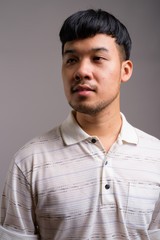 Portrait of young Asian man against gray background