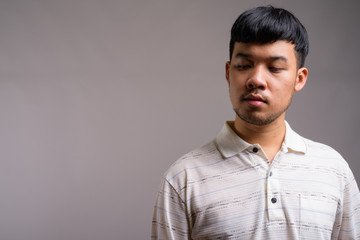 Portrait of young Asian man against gray background