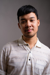 Fototapeta premium Portrait of young Asian man against gray background