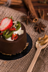 Cake with fruit on a wooden table and burlap. Dessert with berries, cinnamon and nuts