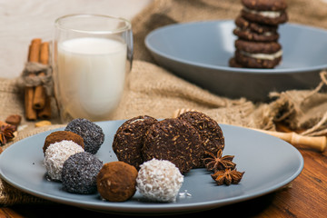 Candy and biscuit on a blue plate. Sweets on the fabric. A glass of milk