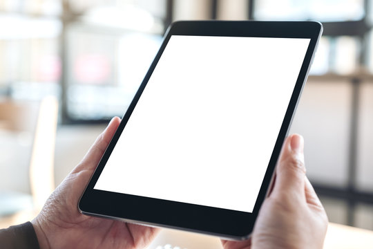 Mockup image of hands holding and using black tablet pc with blank white desktop screen