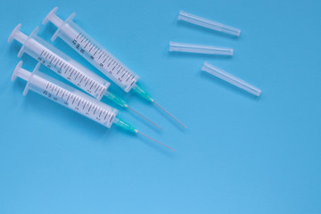 Obraz premium Medical plastic syringes with a needles on blue background. Therapy concept. Selective focus